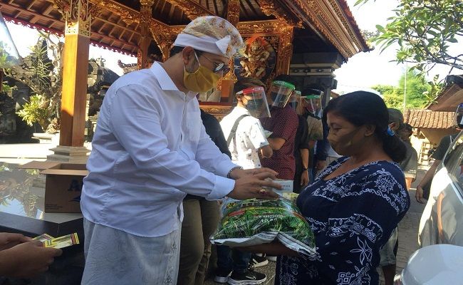 Agung Manik Danendra atau AMD (udeng putih) saat menyerahkan bantuan beras dan vitamin kepada para pedagang di Lingkungan Banjar Paang Tengah, Kelurahan Penatih, Denpasar Timur, Sabtu (27/6). Agung Manik Danendra atau AMD (udeng putih) saat menyerahkan bantuan beras dan vitamin kepada para pedagang di Lingkungan Banjar Paang Tengah, Kelurahan Penatih, Denpasar Timur, Sabtu (27/6).