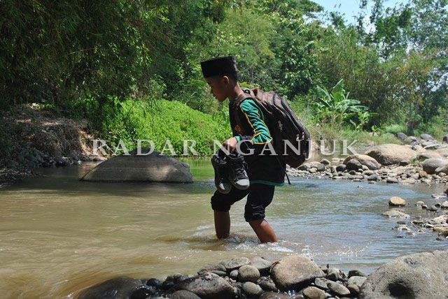 JANGAN BASAH: Siswa Madrasah Ibtidaiyah (MI) harus membawa sepatu agar tidak basah saat menyeberang Sungai Kuncir. Sungai