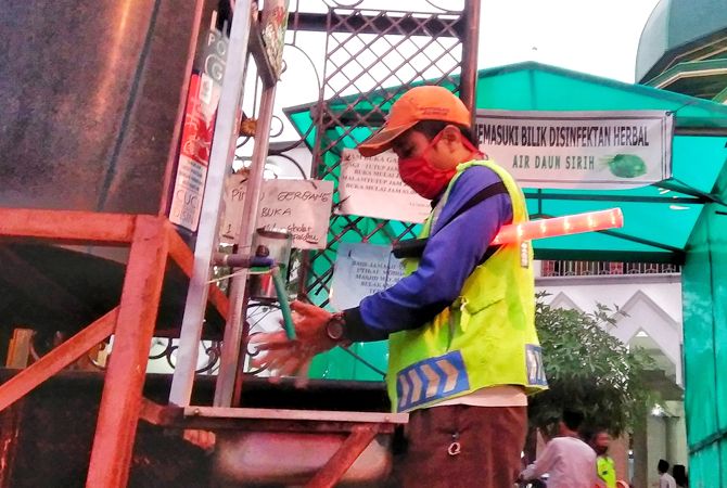 PATUH PROTOKOL: Petugas parkir Masjid Jami Lasem cuci tangan di depan bilik disinfektan herbal kemarin. PATUH PROTOKOL: Petugas parkir Masjid Jami Lasem cuci tangan di depan bilik disinfektan herbal kemarin.