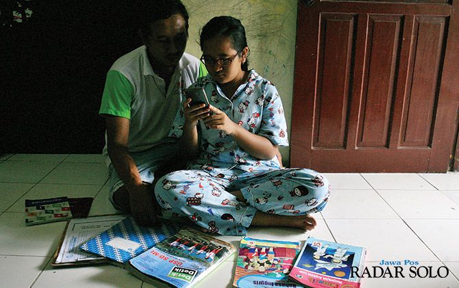 Seorang siswa dibimbing orang tua tengah belajar di rumah dengan sistem daring.