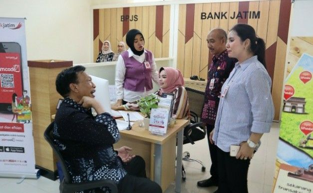 PELAYANAN: Bupati Sambari didampingi Manajer Pemasaran Bank Jatim Gresik, Heni berdialog dengan pemohon izin di stan DPM-PTSP.