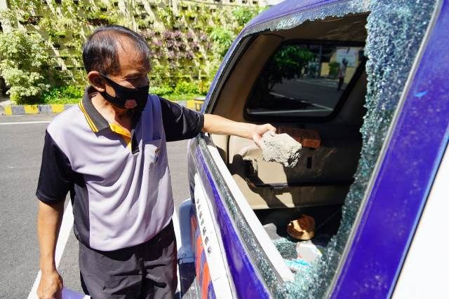 BOLONG: Petugas menunjukkan batu yang dilempar tersangka untuk merusak kaca belakang mobil patroli polisi saat rusuh razia PPKM di Bulak Banteng. BOLONG: Petugas menunjukkan batu yang dilempar tersangka untuk merusak kaca belakang mobil patroli polisi saat rusuh razia PPKM di Bulak Banteng.