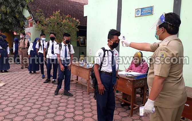AGAR AMAN: Seorang guru yang sedang mengecek suhu tubuh salah satu siswi SMPN 4 Panggul. AGAR AMAN: Seorang guru yang sedang mengecek suhu tubuh salah satu siswi SMPN 4 Panggul.